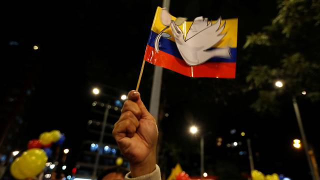 Un hombre alza una bandera Colombiana con la paloma de la paz tras el acuerdo de paz entre el gobierno colombiano y las FARC, en Bogotá.
