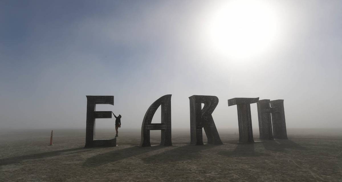 Una participante se cuelga de la letra E de la palabra Earth (Tierra), una de las esculturas del desierto de Black Rock, en Nevada, por el festival Burning Man.