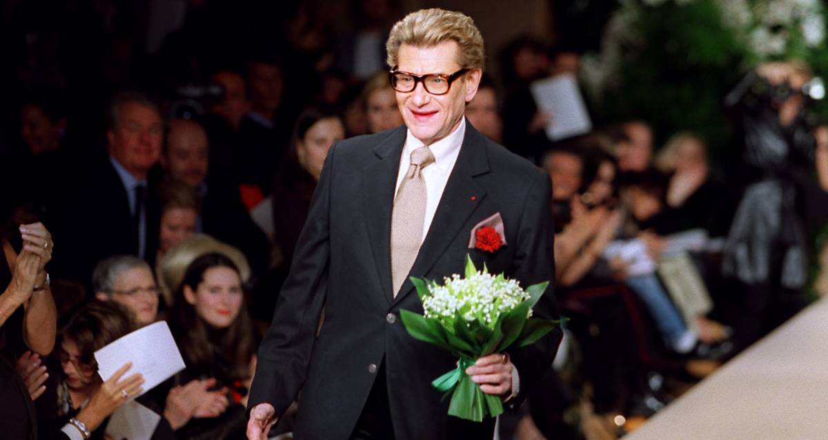 Yves Saint Laurent lleva un ramo de flores a Laetitia Casta al final del pase de la colección primavera-verano 2001 en París.