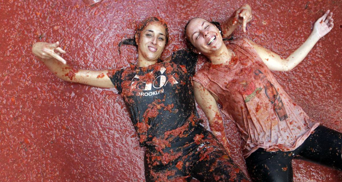 Dos chicas posan sobre pulpa de tomate en la fiesta anual de la 'Tomatina' en Buñol (Comunidad Valenciana).