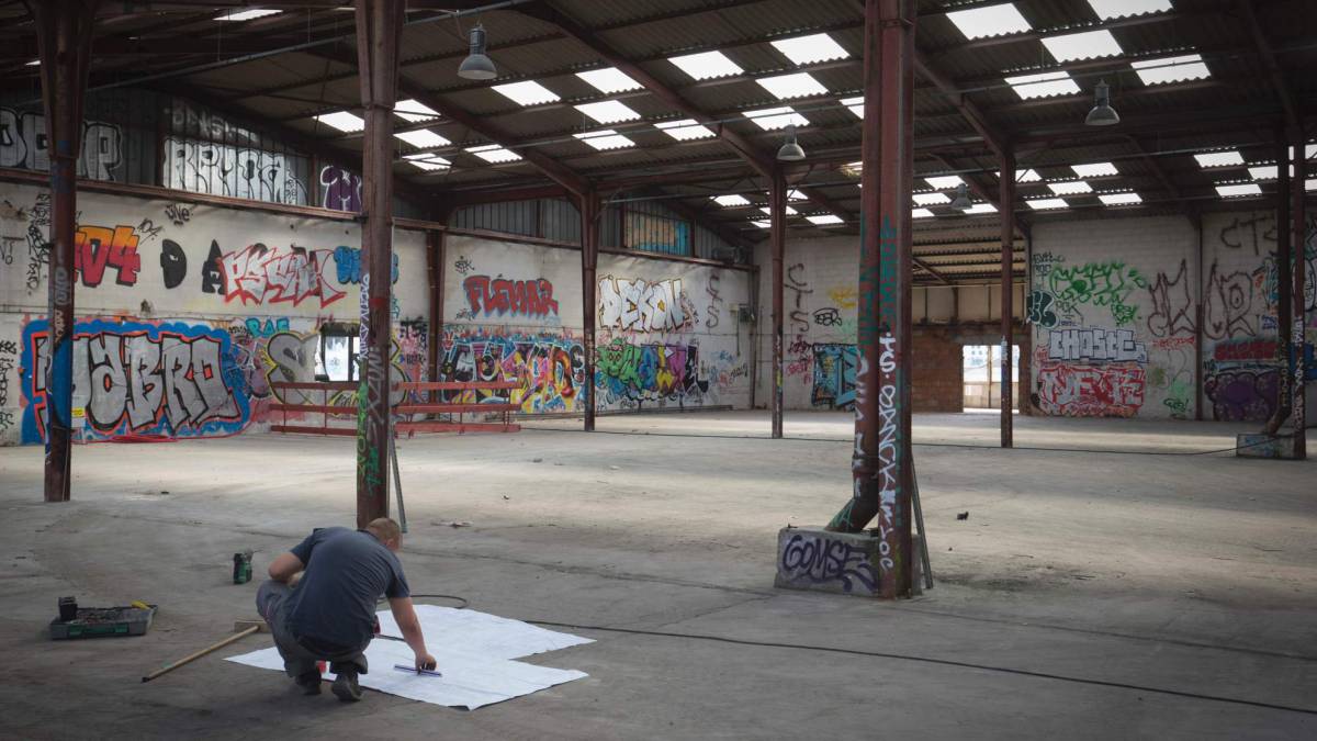 Un trabajador comprobando los planos de construcción en el lugar donde se creará un campamento habilitado para los refugiados, en París (Francia).