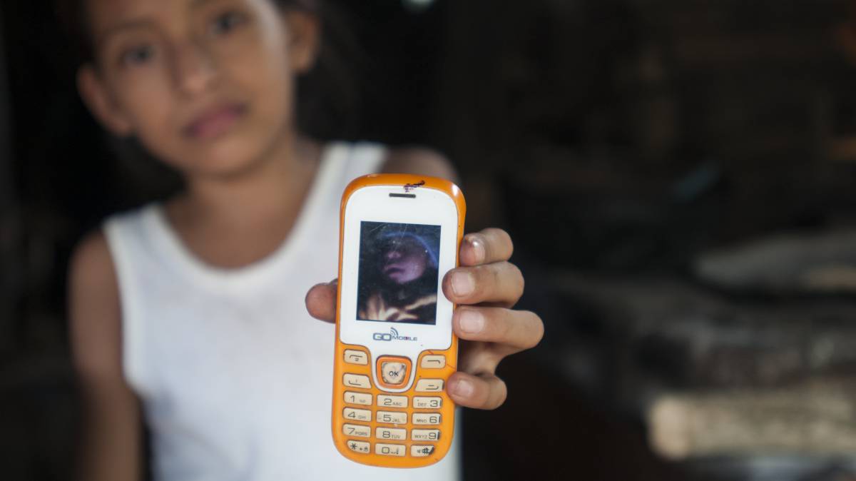 Una niña muestra la foto de su sobrino, que nació con microcefalia.