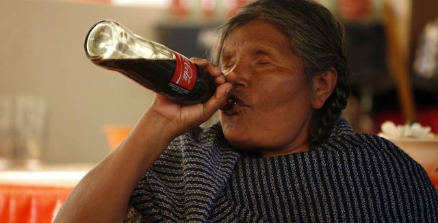 A Mazahua woman drinking Coca-Cola.
