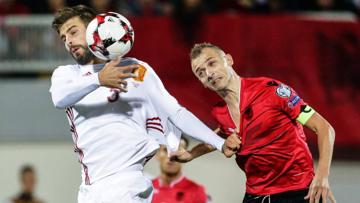 Gerard Piqué y Ansi Agolli luchan por el balón.