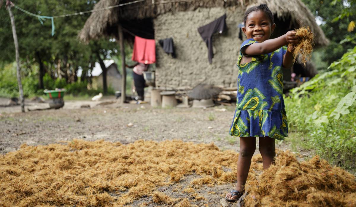 Una niña recoge la paja para hacer fuego en el hogar, en sierra Leona.