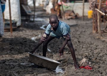 Un niño sostiene un barreño en una de las calles embarradas del campo de desplazados de Malakal, Sudán del Sur.
