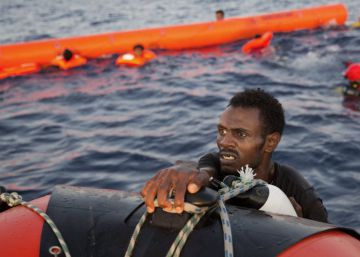 Un migrante eritreo se agarra a un bote salvavidas despu&eacute;s de haber saltado al agua desde una patera durante esta operaci&oacute;n de rescate, a 13 kil&oacute;metros al norte de Sabratha (Libia). 