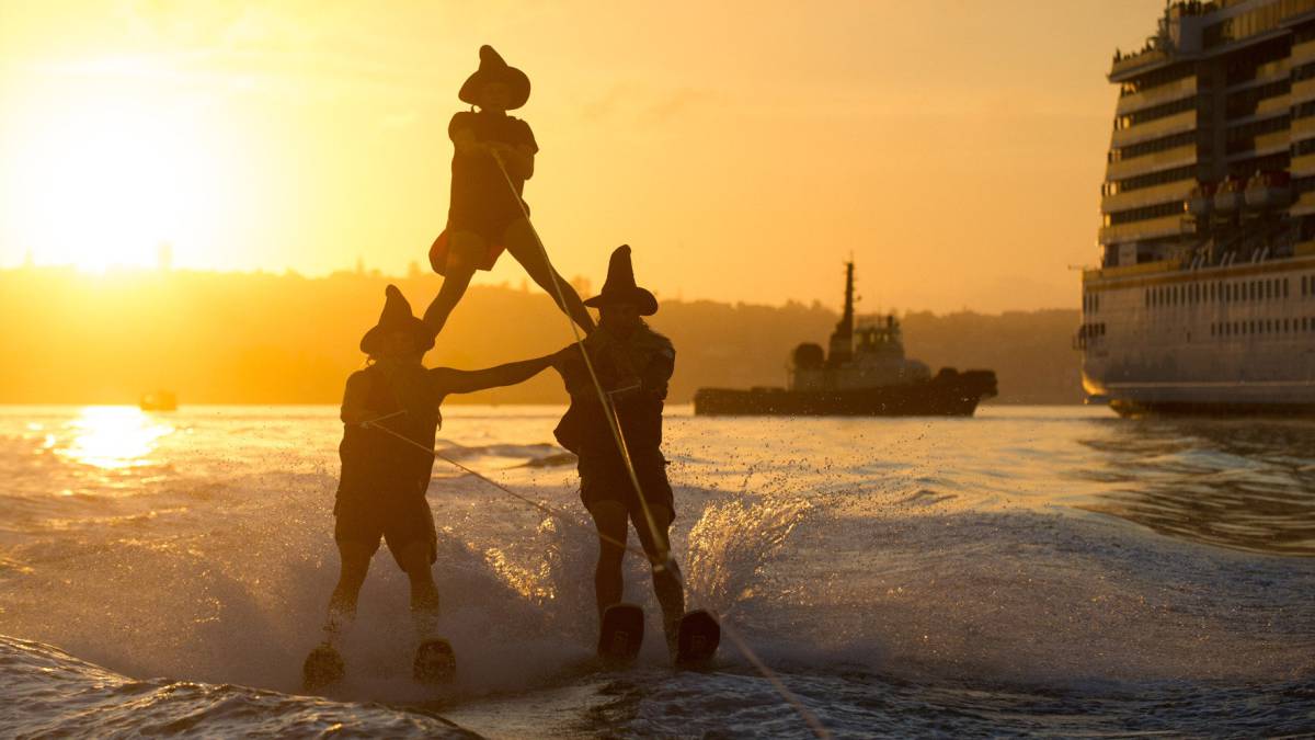 Varias personas practican esquí acuático disfrazadas de brujas, en el puerto de Sydney (Australia).