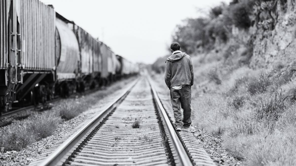 Un hombre camina por la vía por donde pasa La Bestia-Ferromex, un tren de carga que lleva migrantes a través de México.