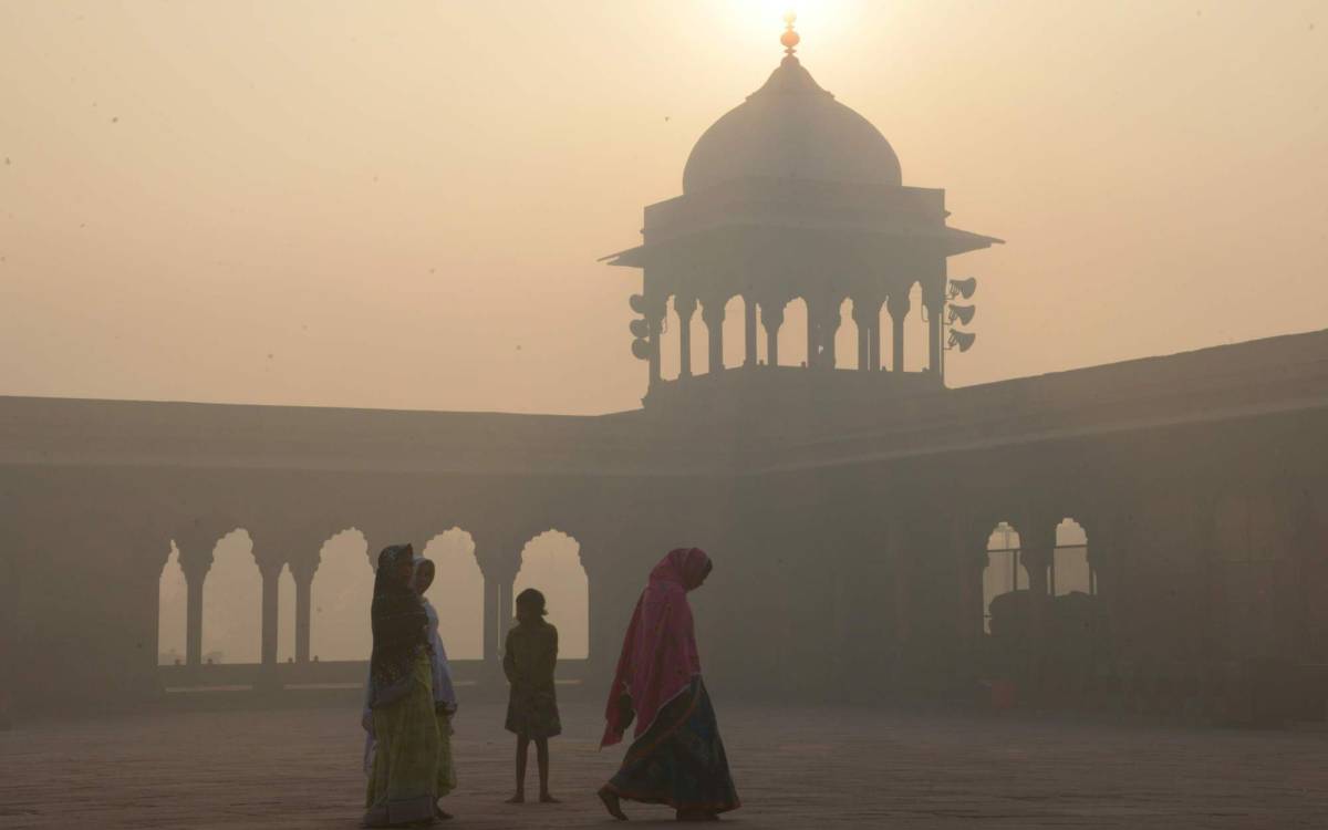 Tres mujeres indias caminan por la aljama Masjid en una tarde de niebla en Nueva Delhi.