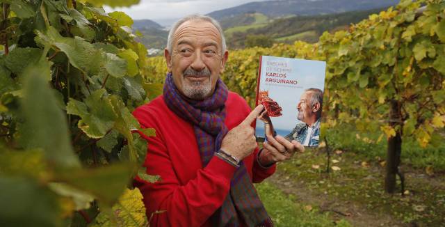Karlos Argui&ntilde;ano posa con su &uacute;ltimo libro en el vi&ntilde;edo de su bodega de chacol&iacute;.