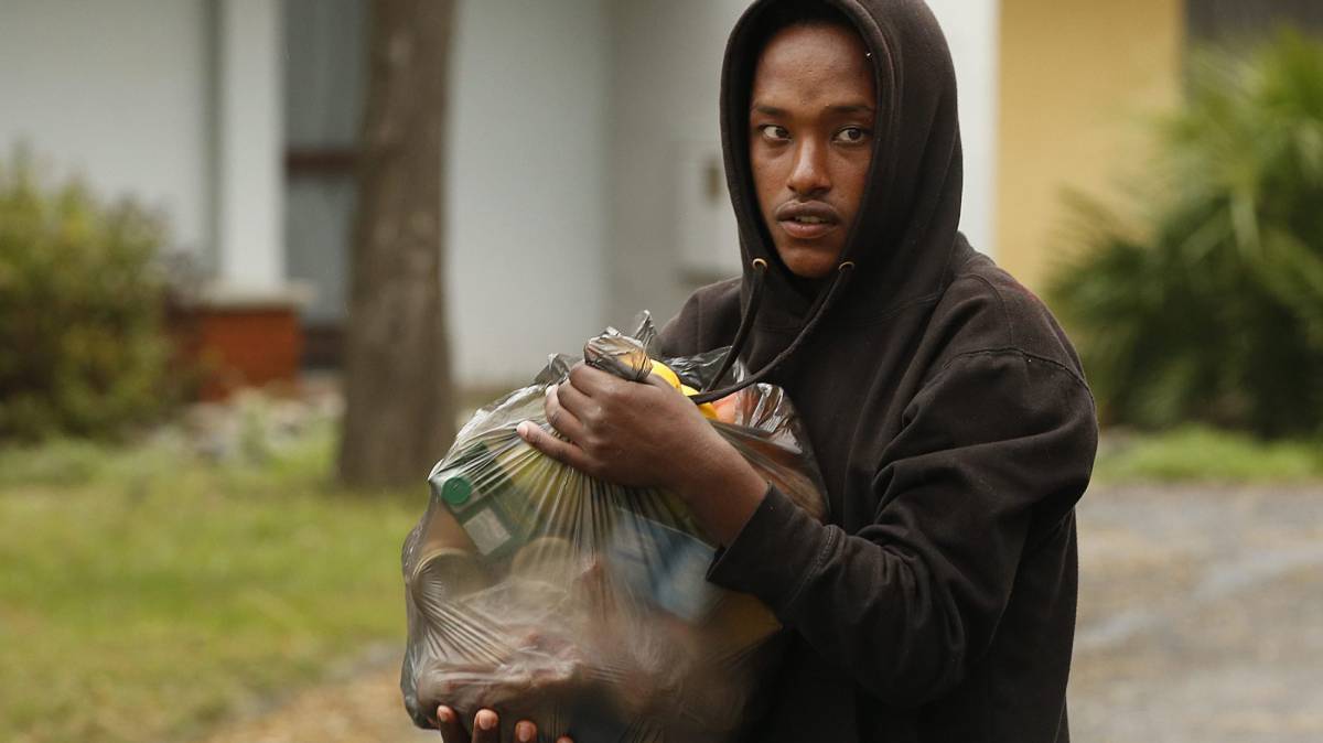 Un inmigrante recibe una bolsa de alimentos del Centro de Comunidad para la Acción Social en la recepción del centro en Sainte-Marie-La-Mer, Francia.