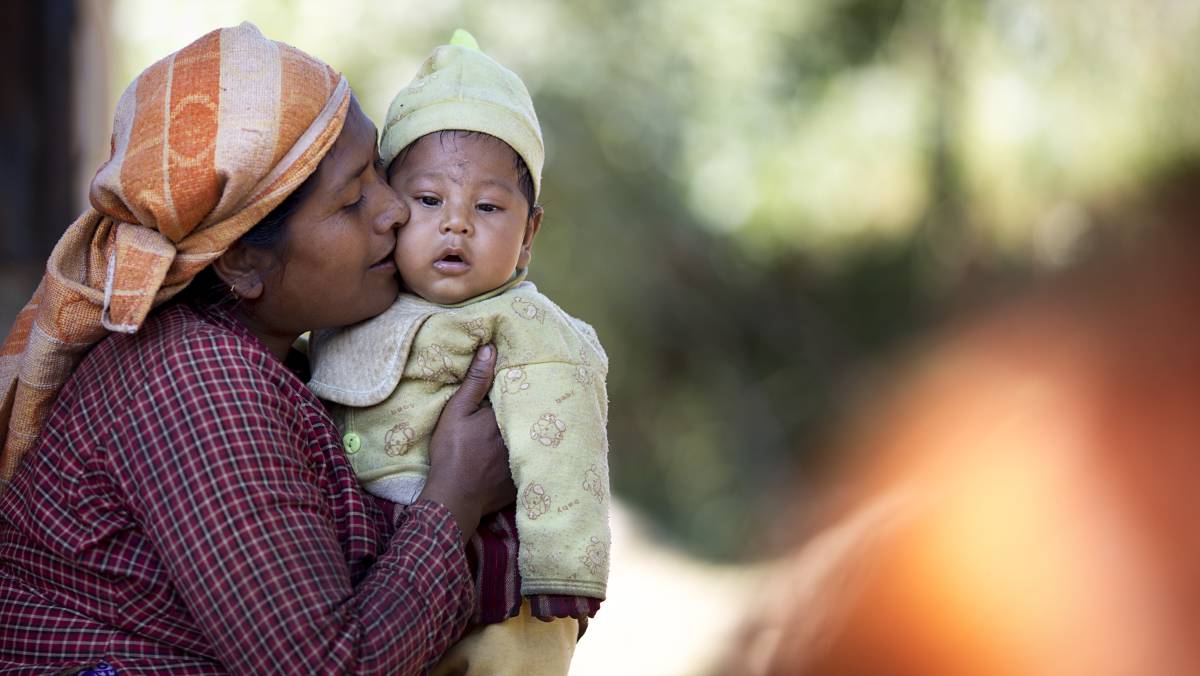 Una mujer besa a su bebé en la puerta de su vivienda, en una zona rural en Sindhupalchowk, Nepal.