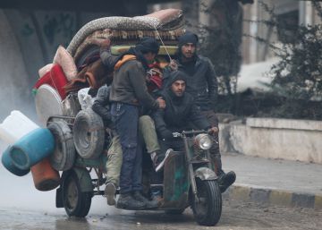 Un grupo de hombres, junto con sus enseres, huyen de Alepo.