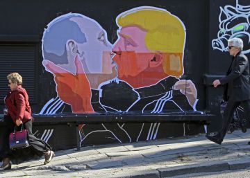 Gente paseando ante un mural en el que aparece el Presidente electo Donald Trump y el Presidente ruso Vladimir Putin rn rn  rn 