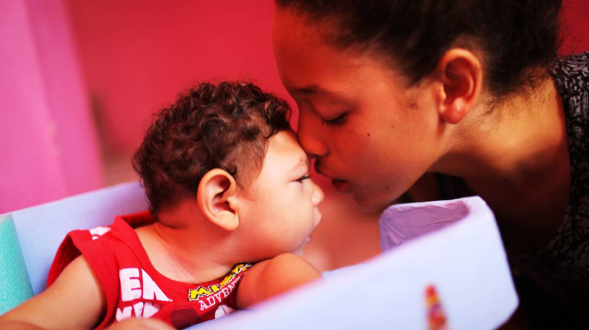 Un beb&eacute; con microcefalia recibe un beso de un familiar.