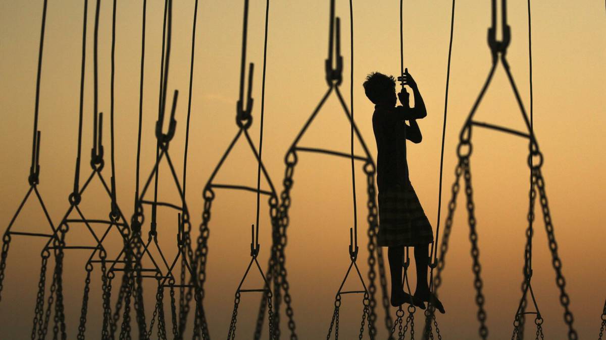Un niño indio juega en uno de los puestos de un parque de atracciones a la espera de clientes durante la feria anual Mahim, en Bombay (India).