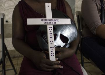 Una mujer haitiana sujeta una cruz durante la celebraci&oacute;n del d&iacute;a de todos los santos en Tijuana.
