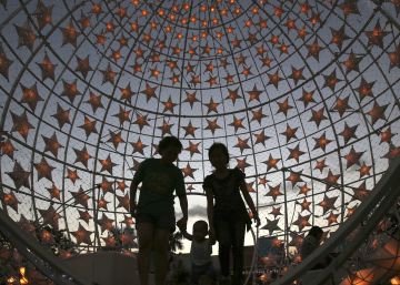 Unos transeuntes, dentro de una exhibici&oacute;n de Navidad encendida en un parque en Pasay, al sur de Manila, Filipinas, el jueves, 22 de diciembre de 2016.