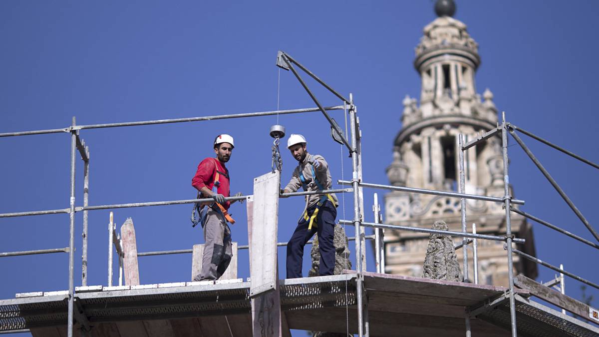 Dos obreros en un andamio en las labores de rehabilitación de la fachada de la Catedral de Sevilla.