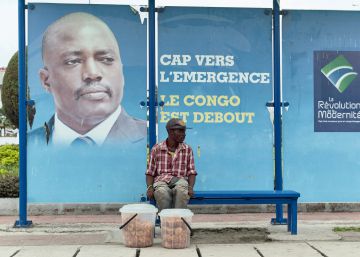Un vendedor, sentado en una parada de autob&uacute;s con una imagen del presidente Joseph Kabila en Kinshasha, RD Congo. 