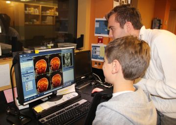 Uno de los investigadores enseña a un niño imágenes de su cerebro que acaban de ser tomadas por un escáner.