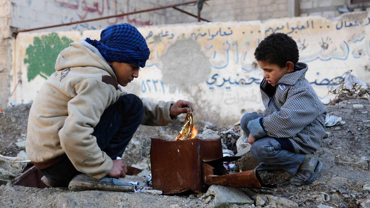 Dos niños hacen un fuego en la zona rebelde de Kafr Batna (Siria).