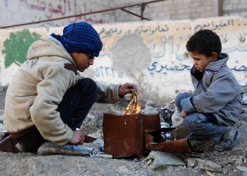 Dos ni&ntilde;os hacen un fuego en la zona rebelde de Kafr Batna (Siria).