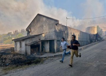 Dos hombres corren durante un incendio forestal, en Concepci&oacute;n (Chile).