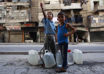 El pasado seis deoctubre, Abdulghani, de nueve a&ntilde;os (izquierda) y su hermano Hassan, de seis, esperan su turno para rellenar sus bidones con agua de un pozo en la calle en la parte este de Alepo (Siria). rn 