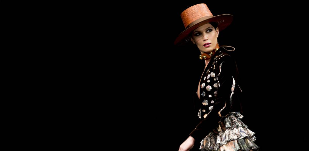 Una modelo con sombrero de copa alta mueve los volantes de su falda estampada.