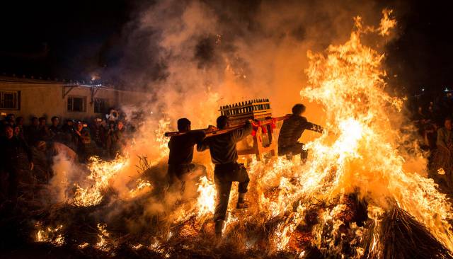 Cuatro hombres transportan un santuario antes de saltar un fuego durante las celebraciones de del Año Nuevo Chino, en Jieyang (China).