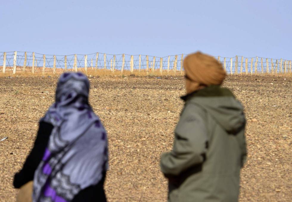 Dos personas contemplan la valla que separa las zonas controladas por Marruecos y el Frente Polisario en el Sáhara Occidental.