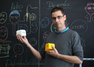 Juan González sostiene dos piezas de robots diseñadas por él mismo.