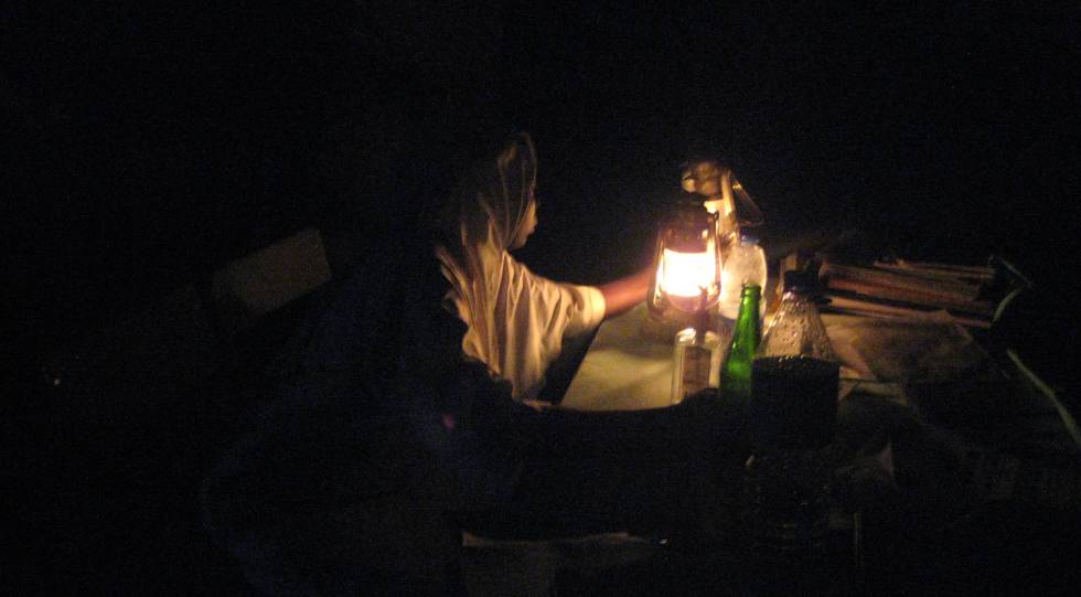 Un matrona hace guardia alumbrada solo con una lámpara de keroseno.