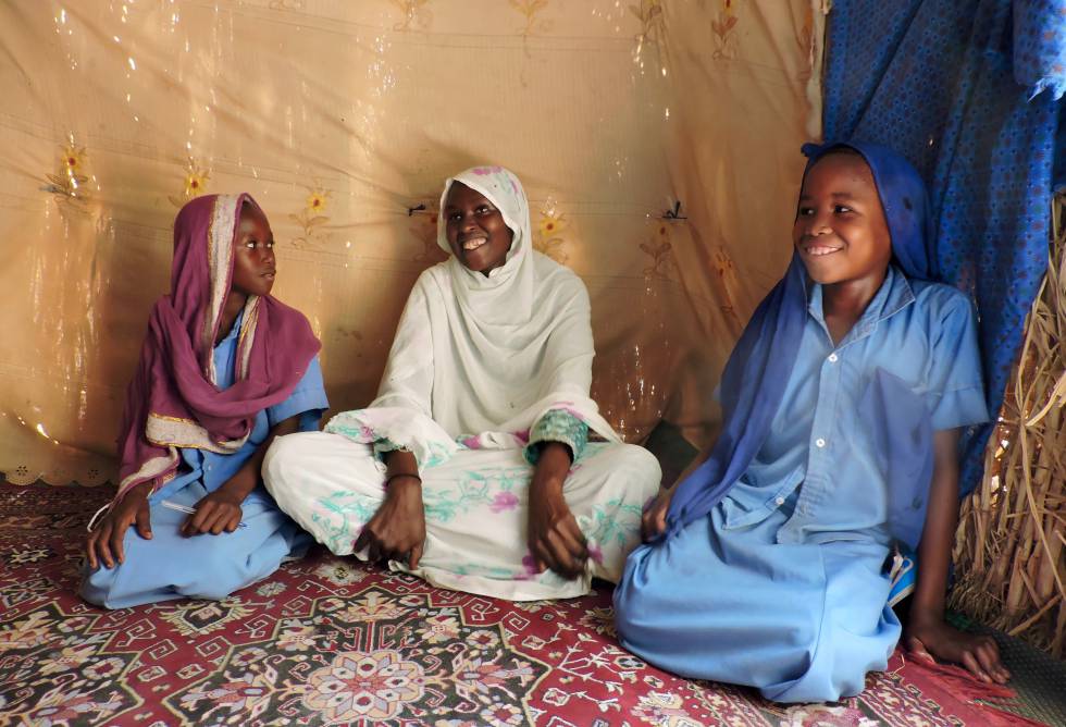 Sena, de 30 años, flanqueada por dos de sus hijas vestidas con el uniforme escolar en su casa de Bol (Chad).