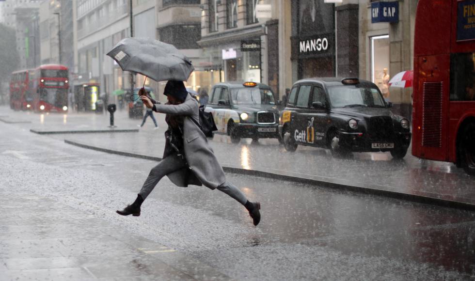 Una chica salta sobre un charco creado tras la lluvia en Londres.