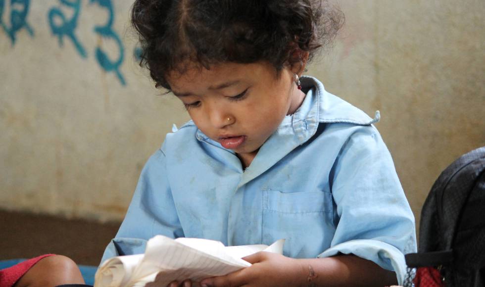 Una niña lee en su cuaderno en una escuela rural de Nepal.