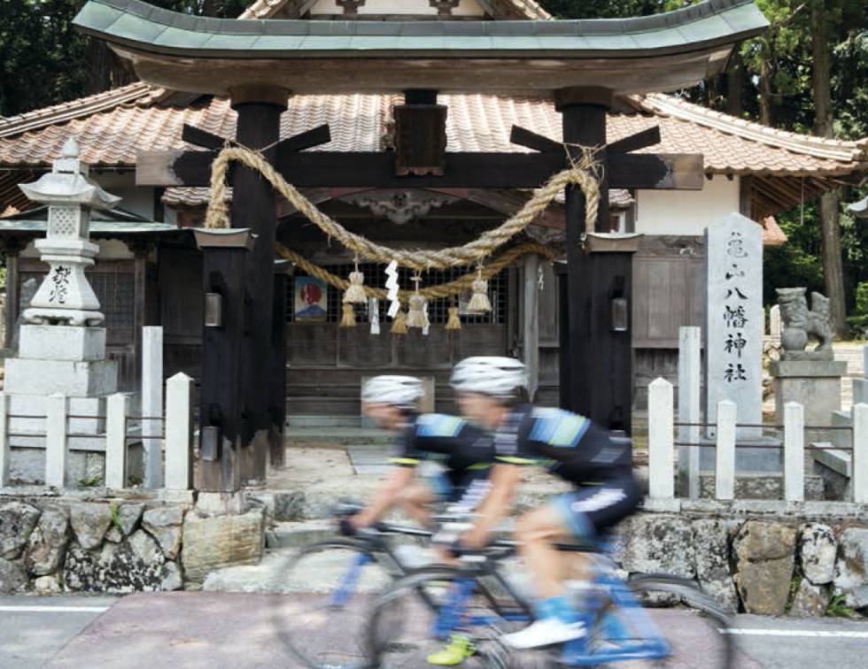 Una pareja de ciclistas pasa frente a un templo en Japón