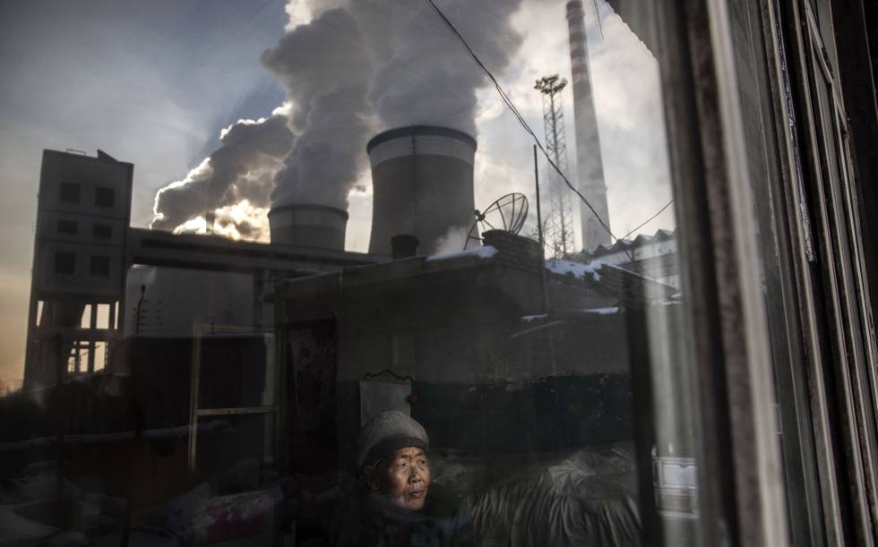 Un hombre en su casa, junto a una planta de carbón en Shanxi (China).