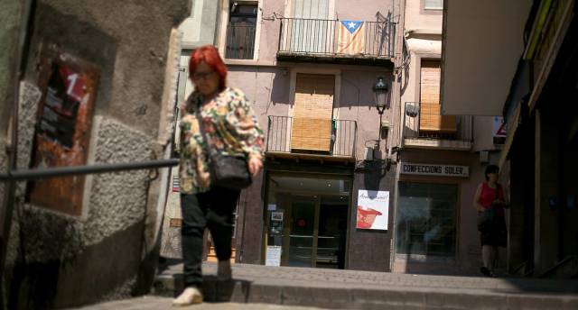 Una mujer camina por una calle de Berga con una estelada al fondo.