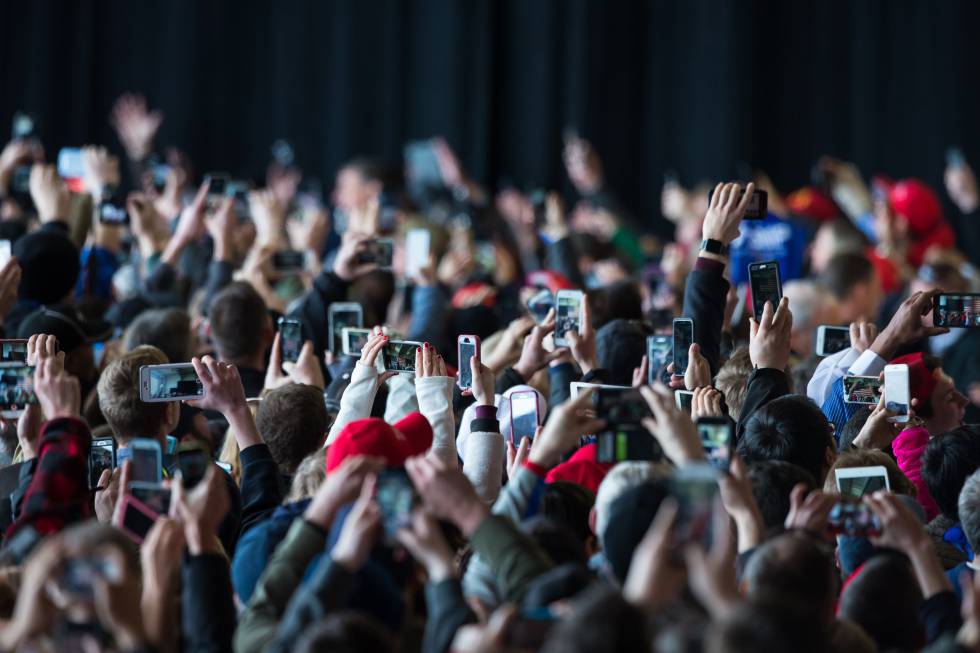 Una multitud fotografía un acto con su móvil. rn rn 
