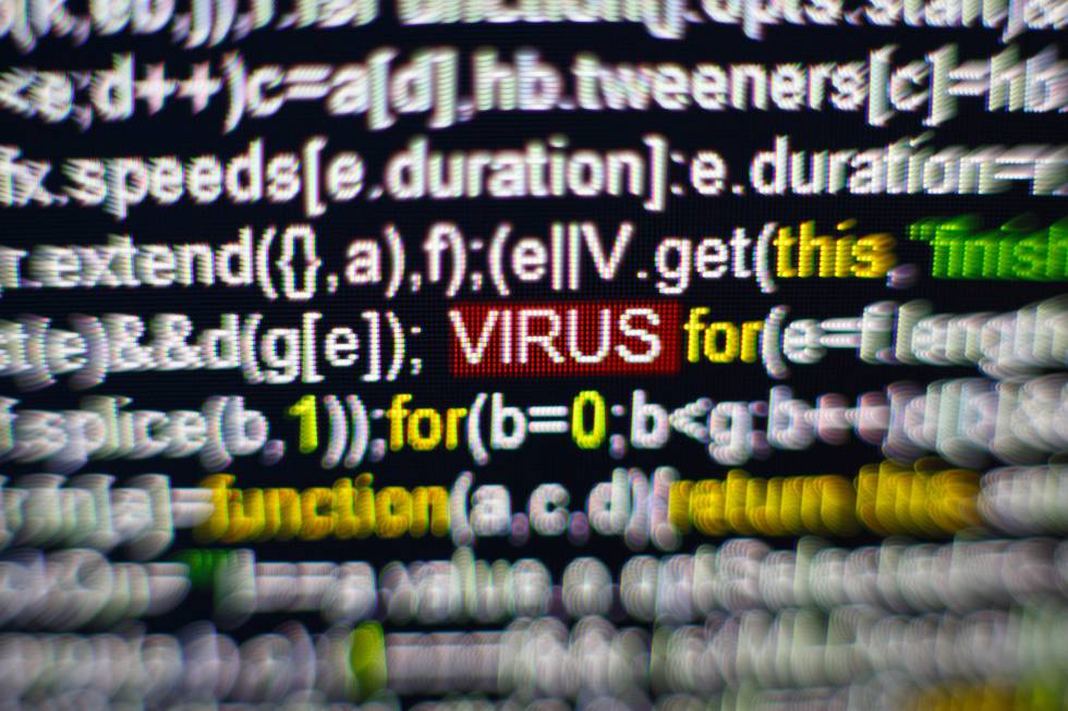 Foto de macro de la pantalla de la computadora con el código fuente del programa y la inscripción VIRUS destacada en el medio.