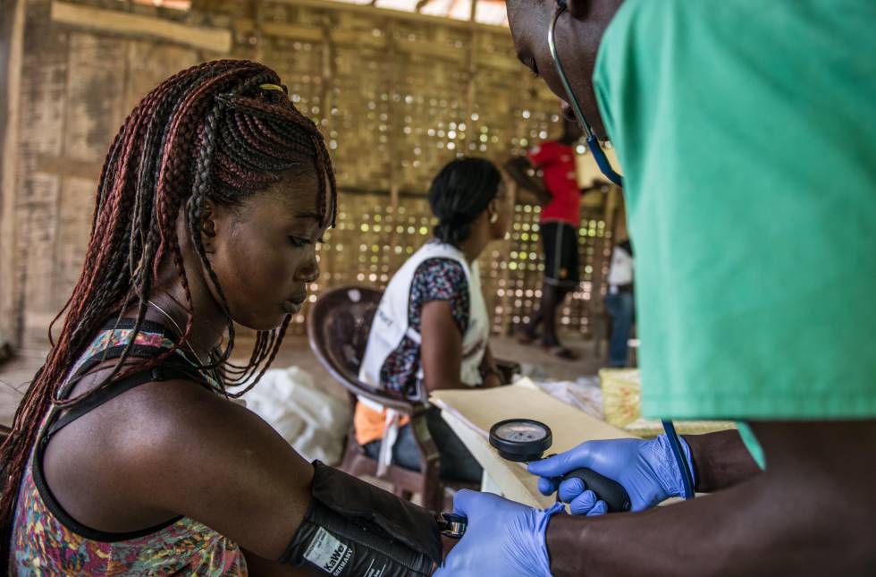 Un médico toma la tensión a una paciente en Sierra Leona.