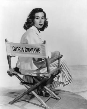 La actriz americana Gloria Grahame sentada en una silla de rodaje con su nombre en 1955.
