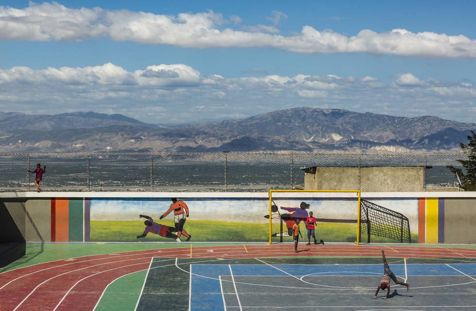 Niños de la barriada juegan en un polideportivo. Al fondo, panorama de Puerto Príncipe, la capital.