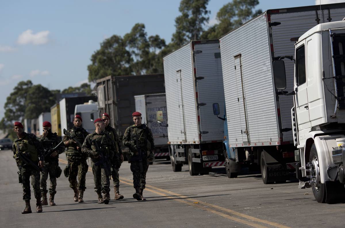 Un grupo de militares pasa junto a varios camiones parados por la huelga.