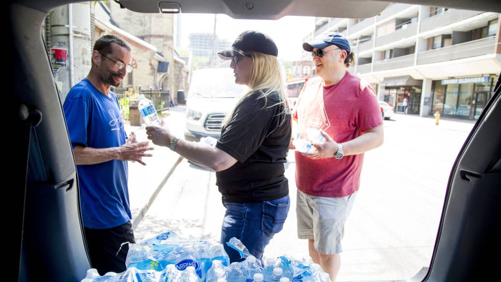 Uma mulher distribui garrafas de água em Toronto, no dia 30 de junho, durante a onda de calor no leste Canadá.