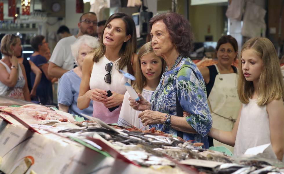 La reina Letizia, la infanta Sofía, la reina Sofía y la princesa Leonor observan el género en una pescadería del mercado del Olivar, en Palma de Mallorca.