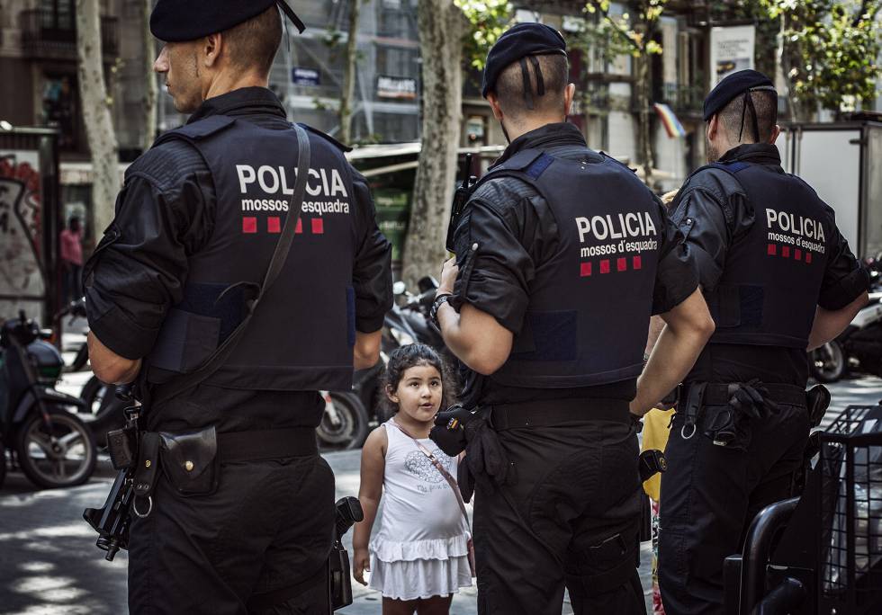 Una niña mira a una pareja de Mossos en La Rambla.